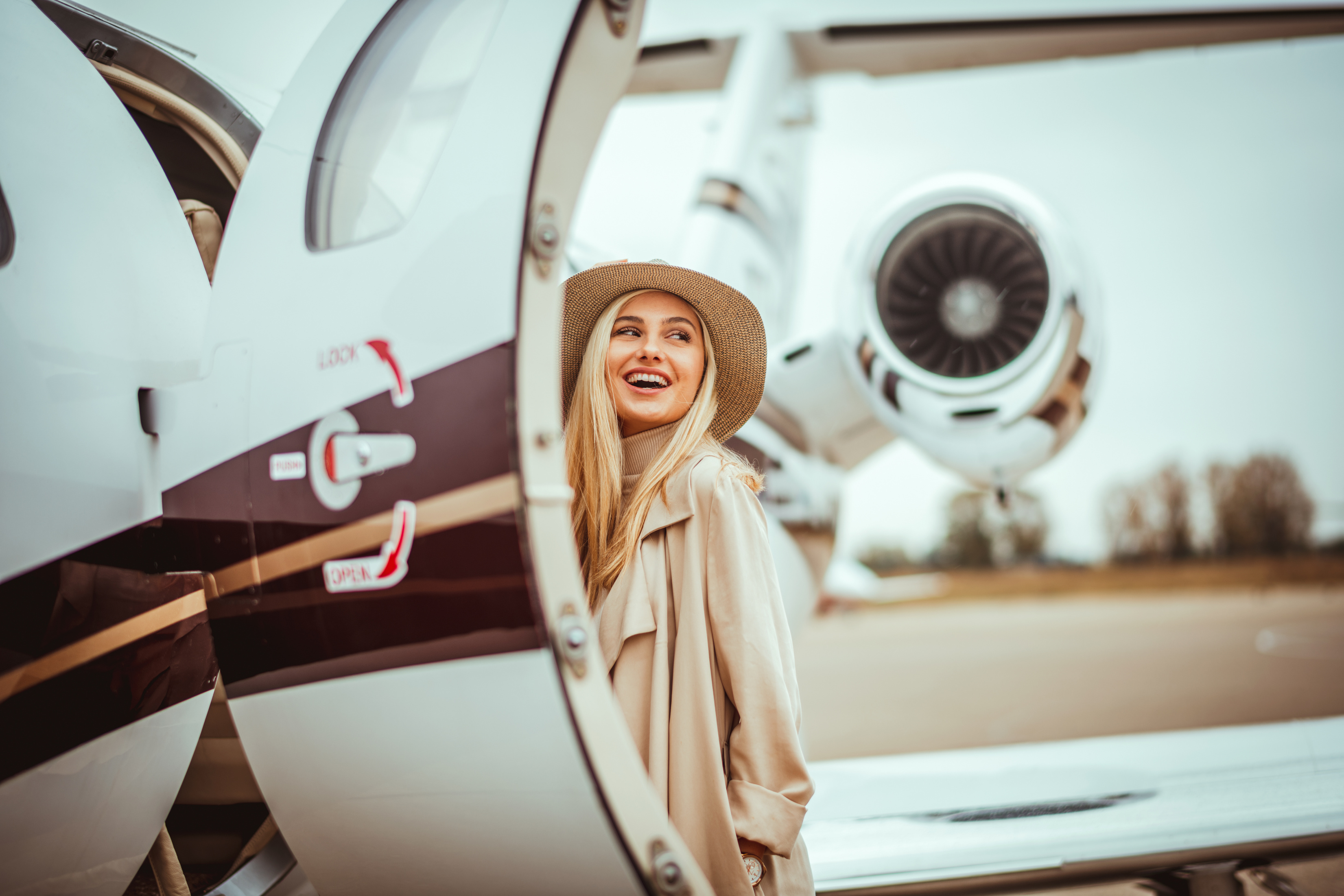 Young rich woman entering a parked private airplane